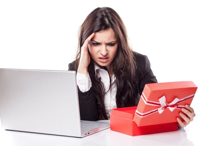 パソコンと空いたプレゼントを見て困惑する女性